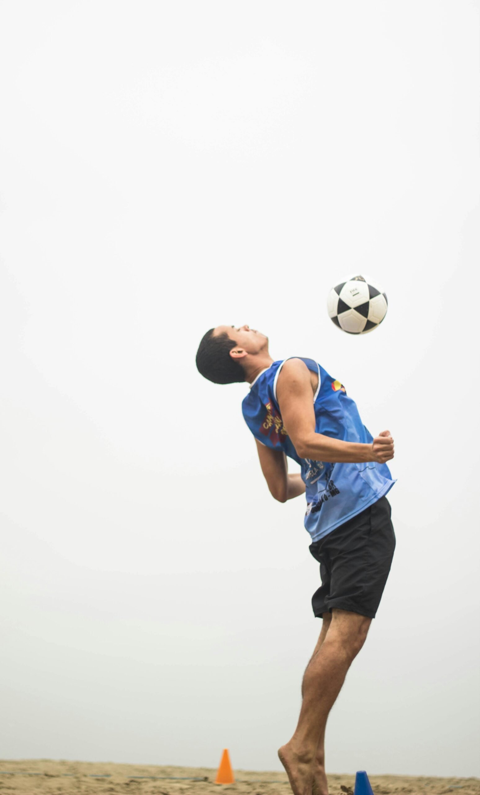 A young man dynamically performs a soccer trick outdoors, emphasizing speed and agility.